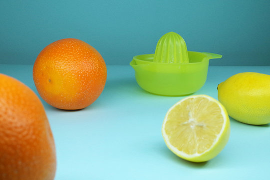 Yellow fruit juicer with lemons and oragnes on cyan background