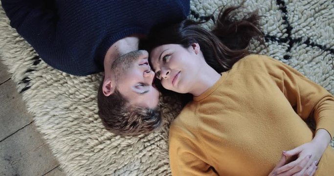 Couple lying down on rug in new home