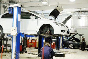 Car on a lift in a car repair station - obrazy, fototapety, plakaty