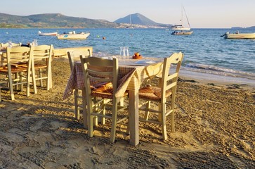 Fototapeta na wymiar Table set on the beach at a traditional Greek taverna restaurant in Messenia, Greece