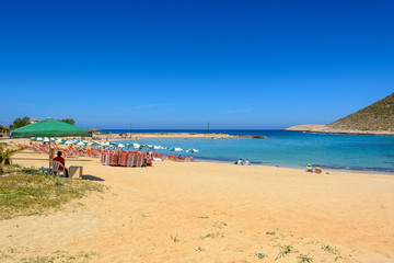 Fototapeta na wymiar Tourists relax and bath on the Stavros beach, made famous by Anthony Quinn the film Zorba the Greek. Crete island, Greece. 