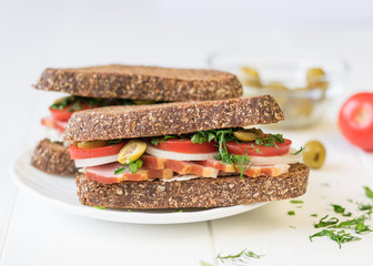 Freshly made ham sandwich on a white wooden table.