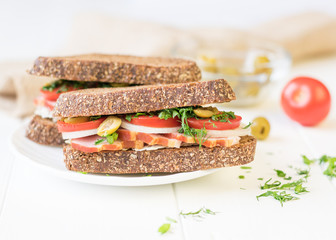 Freshly made ham sandwich on a white wooden table.