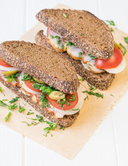 Freshly made ham sandwich on a white wooden table.