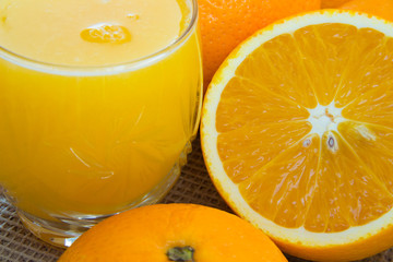 A glass of juice and oranges close-up