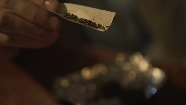 Closeup of male hands rolling joint, marijuana legalization for recreational use