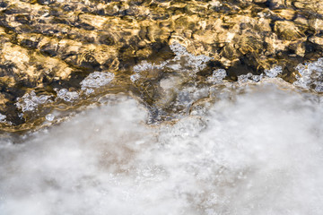 Eisscholle am Flussufer ragt ins Wasser hinein