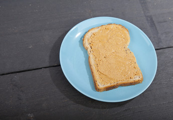 Bread with peanut butter on wooden background