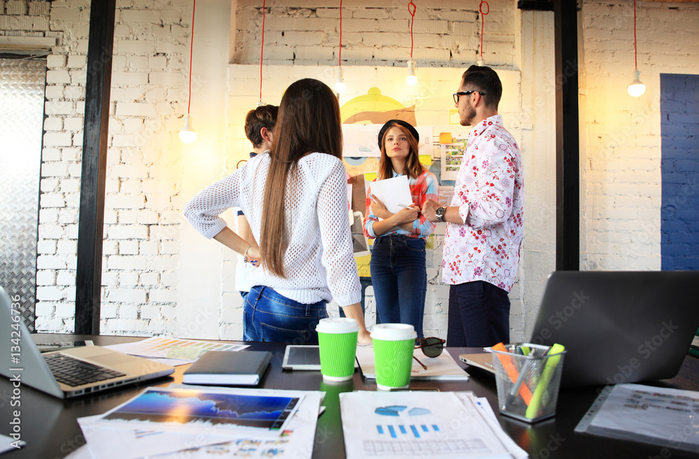 Wall mural portrait of happy young people in a meeting looking at camera and smiling. young designers working t