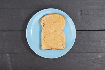 Bread with peanut butter on wooden background