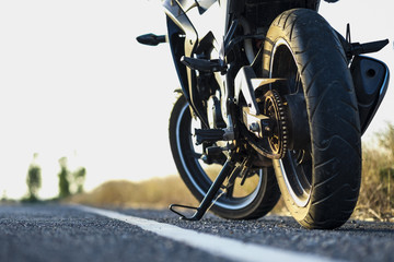 Plakat A motorcycle parking on the road right side and sunset, select focusing background.