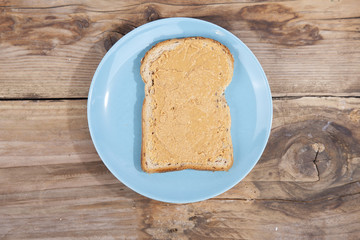 Bread with peanut butter on wooden background
