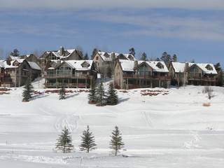 Cross country skier moves across snowy meadows under large houses Colorado