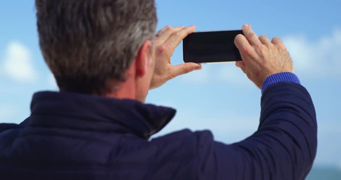 Mature man taking picture of view from mobile phone