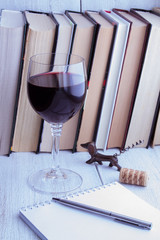 Books, glass of red wine on an old wooden table
