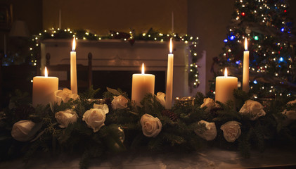Candles in floral centerpiece on table at Christmas time with a tree in the background
