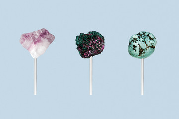 Three stones on a stick isolated on a blue background. Art work, where the stones is look like candy on a stick