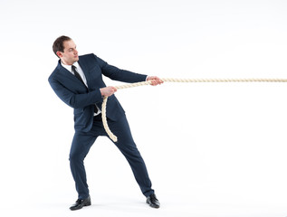 Strong and confident business leader. Side view of businessman in suit pulling a rope while standing against white background