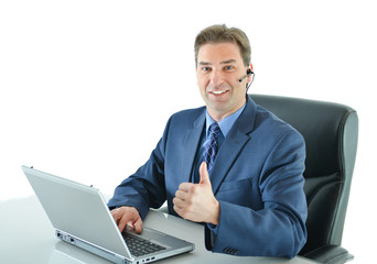 Business man on a call while working on laptop and giving big thumbs up or customer service representative helping people with thumbs up