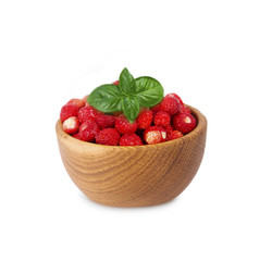 Wild small strawberries in a wooden bowl with basil leaves. Ripe and tasty strawberries isolated on white background. Sweet and juicy berry with copy space for text.