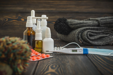 Pills, nose drops a cold treatment, flu runny  on the table with an electronic thermometer