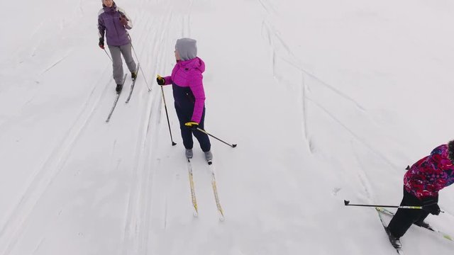 Caucasian mother with grandma and young daughter cross-country skiing on snow. Camera lifting up