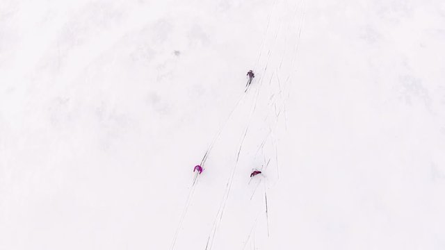 Top view at the three female skiers running on snowy ice of frozen big lake. Camera tracking