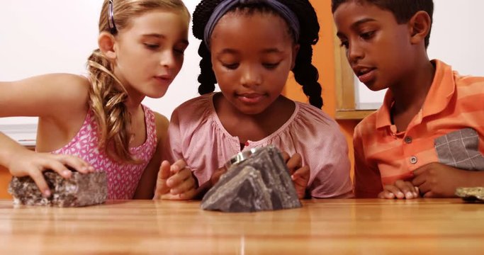 School kids using magnifying glass over rock