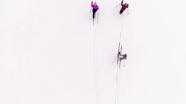 Three skiers running cross-country skis on white snowy field. Top view 