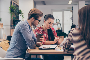 Team of young concentrated students working on project at the co