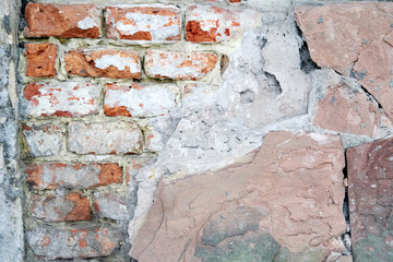 masonry of brick under a layer of old red plaster