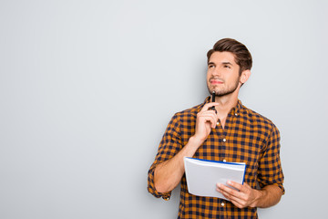 Portrait of minded man with notebook isolated on gray background