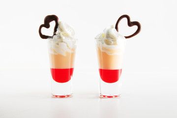 Multi-layered cocktail shot, close-up. Short cocktail with milk, syrup, cream, decorated with heart made of chocolate. Saint valentine's day.