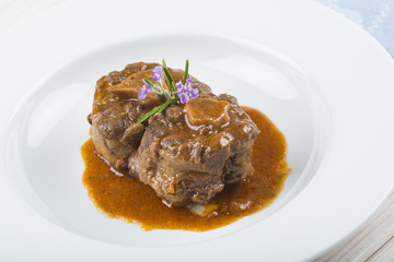 Guiso de carne de rabo de toro o ternera con salsa de verduras y vino tinto decorado con flores de romero para la comida