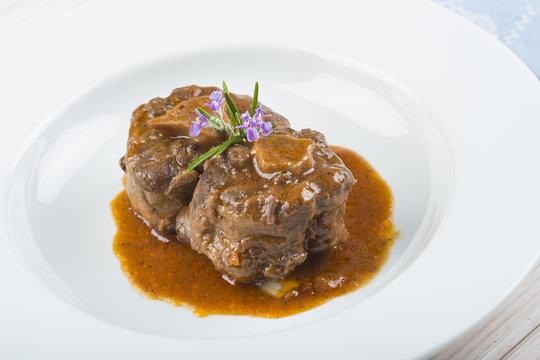 Guiso de carne de rabo de toro o ternera con salsa de verduras y vino tinto decorado con flores de romero para la comida