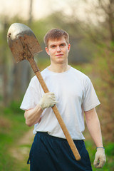 Agronomist handsome strong man with shovel on  background of flo