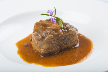Guiso de carne de rabo de toro o ternera con salsa de verduras y vino tinto decorado con flores de romero para la comida