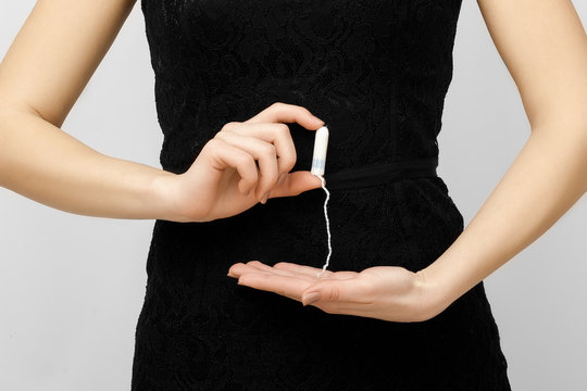 Beautiful young smiling girl with long hair holding a female swab isolated on white background. In his hand of  menstrual tampon     . Menstruation time. Hygiene