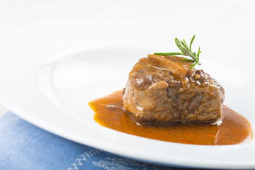 Guiso de carne de rabo de toro o ternera con salsa de verduras y vino tinto decorado con flores de romero para la comida