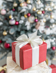 Red gift box and decorated New Year Tree on the background.