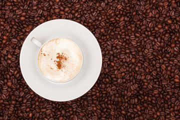 A cup of cappuccino on coffee beans background