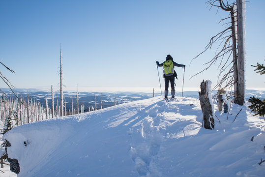 Ein Wanderer erkundet mit Schneeschuhen einen verschneiten Berg bei schönem Wetter