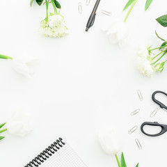Flat lay, top view office table desk. feminine desk workspace frame with notebook, pen, floral bouquet, and clips on white background.