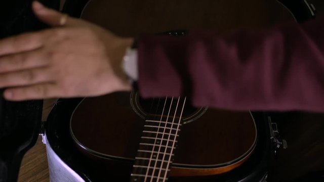 The man pulls out a guitar out of the case
