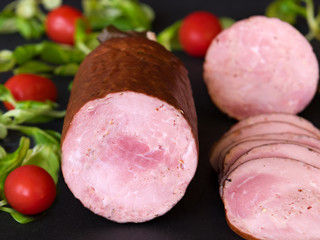 Sausage with arugula and tomatoes on a dark board