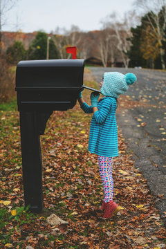 Girl checking a mailbox in the street to see if there is any post, USA