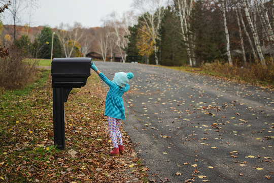 Girl checking a mailbox in the street to see if there is any post, USA