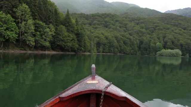 View from the rowboat bow at the calm Biorgadskoe lake and lush mountains. Nature of the Biogradska Gora national park. Montenegro
