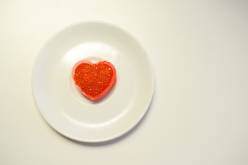 Red caviar in a heart shape on white plate background