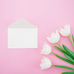 Tulips and envelope on pink background. Flat lay, Top view. Valentines Day background.